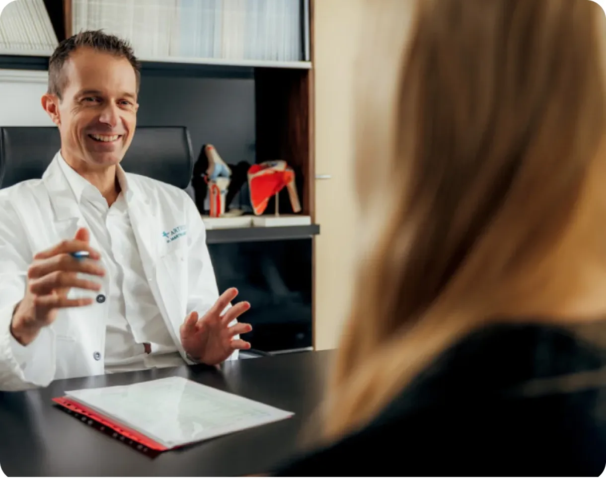 Martin Mikek in conversation with a patient across a consulting-room desk.