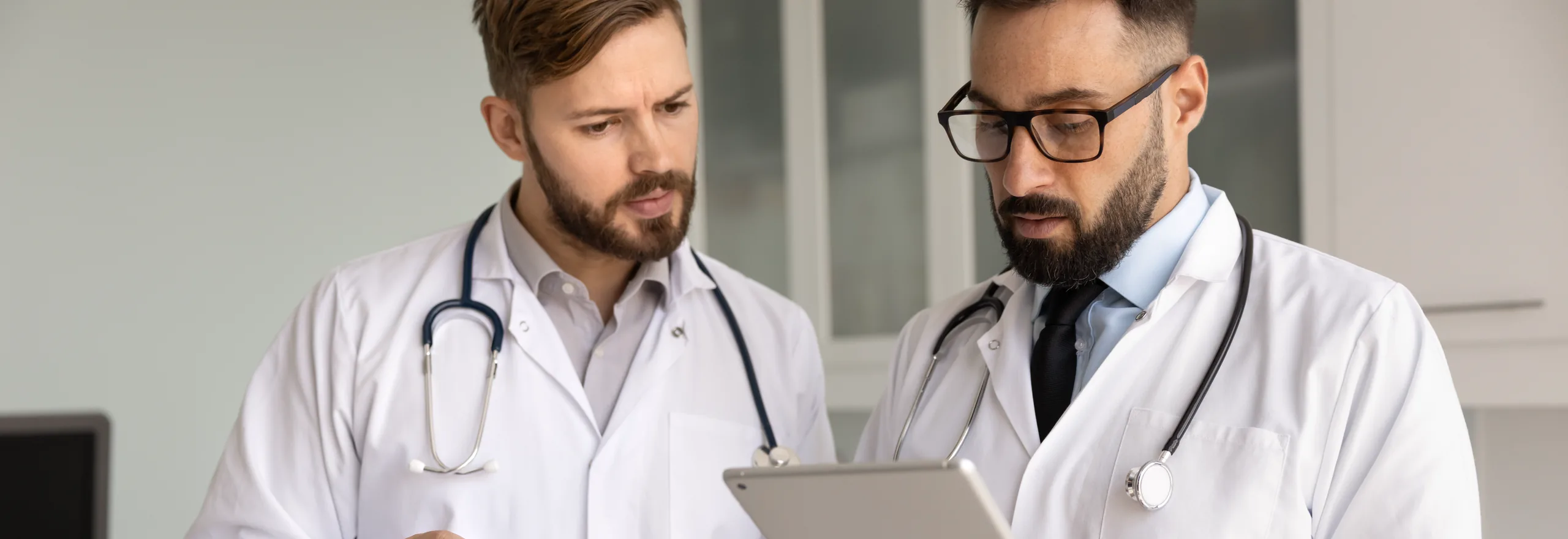 Two clinicians reviewing a patient record together on a tablet.