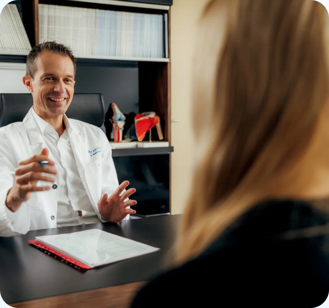 Martin Mikek, MD, in conversation with a patient across a consultation desk.